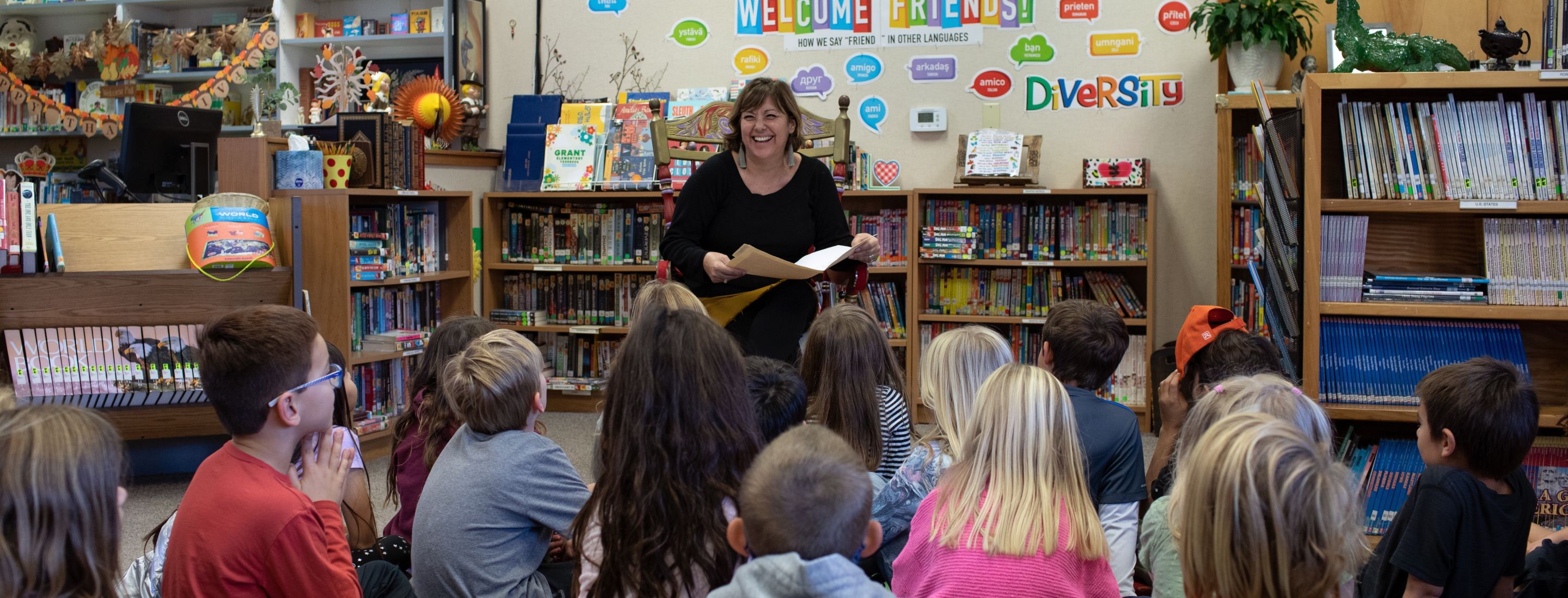 Grant Elementary students sitting on a colorful rug, listening to someone read aloud from a book